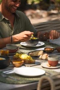 a man sitting at a table with plates of food at Beco das Flores in Mata de Sao Joao +29 photos