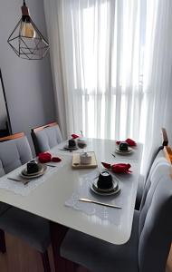 a white dining room table with red roses on it at Paz e natureza! Descanso e tranquilidade! in Rio das Ostras