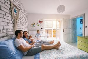 a man and woman sitting on a bed with a baby at Apartmán Malý princ in Dolní Lomná +28 photos