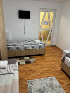 a room with two beds and a door with a television at Casa Leny in Călăraşi +12 photos