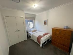 a small bedroom with a bed and a dresser at Guest house Que Sera in Cooranbong