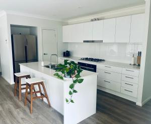 a kitchen with white cabinets and a white counter top at Guest house Que Sera in Cooranbong