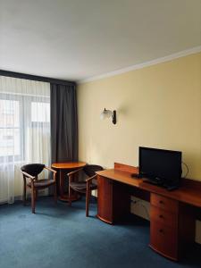 a hotel room with a desk and chairs and a television at Pokoje Stary Rynek in Elblag