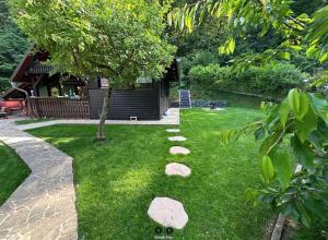 a garden with rocks in the grass with a tree at Hishka Ishka Love in Iška +7 photos