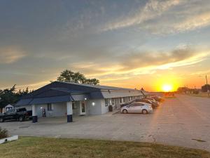 a building with cars parked in a parking lot with the sunset at Gateway Inn in Sullivan