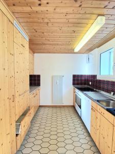a large kitchen with wooden cabinets and a sink at Lakeview-Apartment - Komplette Wohnung mit Seeblick an ruhiger Lage in Weesen +4 photos