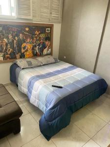 a bed in a room with a painting on the wall at Som do mar Kitinete in São Vicente