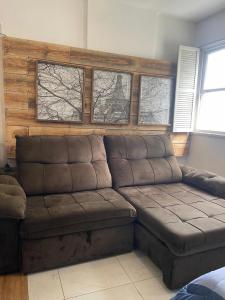 a brown leather couch in a living room with windows at Som do mar Kitinete in São Vicente