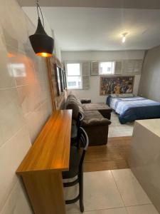 a living room with a table and a bed at Som do mar Kitinete in São Vicente