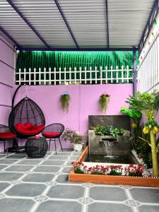 a patio with a fountain and chairs and a pink wall at Ryo Homestay Dốc Lể in Ba Ha