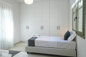a white bedroom with a bed and white cabinets at Villa Selina 4 - Etheras Properties in Kythira