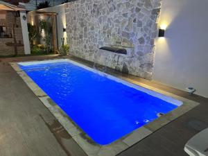 a blue swimming pool in front of a stone wall at Recanto dos Maias in Aracaju
