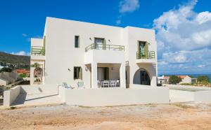 a white house with chairs in front of it at Villa Selina 4 - Etheras Properties in Kythira