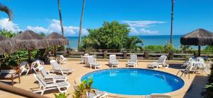 a patio with chairs and a pool and the ocean at Pousada dos Veleiros in Nova Almeida
