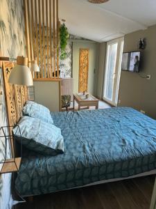 a bedroom with a bed with a blue comforter at Suite 150 m de la mer in Luc-sur-Mer