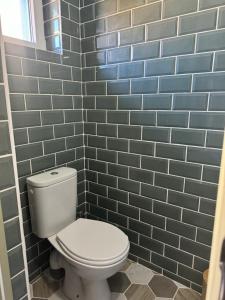 a bathroom with a white toilet and blue tiles at Suite 150 m de la mer in Luc-sur-Mer