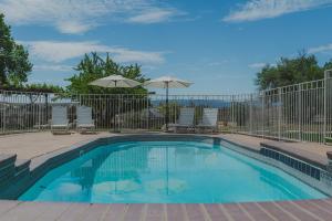 a swimming pool with a fence and chairs and umbrellas at The Vineyard Farmhouse Villa in Paso Robles