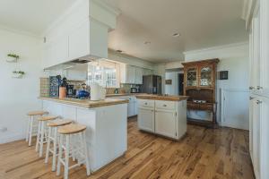 a kitchen with white cabinets and bar stools at The Vineyard Farmhouse Villa in Paso Robles