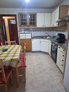 a kitchen with white cabinets and a table with a tablecloth at Piso cerca de la playa in Boiro
