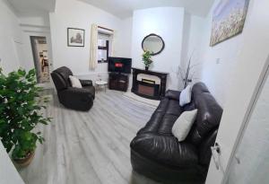 a living room with a leather couch and a fireplace at Derry City Centre Kelly's Place et in Derry Londonderry +14 photos