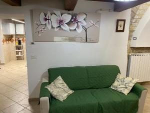 a green couch in a living room with a painting of flowers at Casa Vacanze Sotto Piazza in Gualdo Tadino