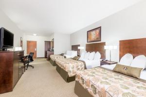 a hotel room with three beds and a flat screen tv at Canalta Olds in Olds