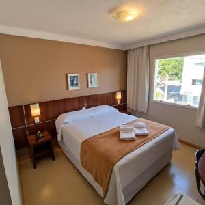 a bedroom with a bed with two towels on it at Hotel Aguadero in Passo Fundo