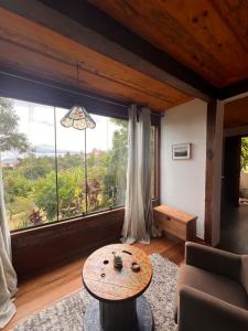 a living room with a table and a large window at Chalé da Mata Lavras Novas in Lavras Novas