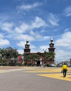 a man walking in front of a building with two towers at hospedaje Maluli suite girasol in Santa Elena +4 photos