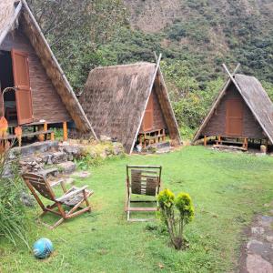 a group of huts with chairs and flowers in the grass at Hay & Mountain Huts in Colcapampa