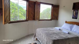 a bedroom with a bed and two windows at Pousada irmãos Calixto in Portalegre