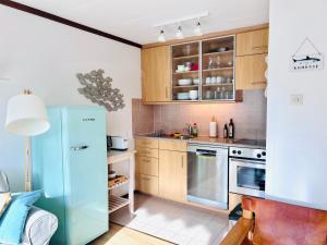 a kitchen with a blue refrigerator and wooden cabinets at Ferienwohnung Westerlicht - Apartment am Leuchtturm - De Torenhoeve in Nieuw-Haamstede