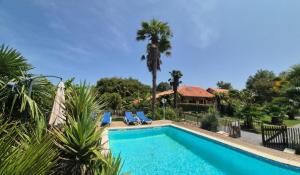 a swimming pool with two chairs and a house at renaissance larmane in Eugénie-les-Bains