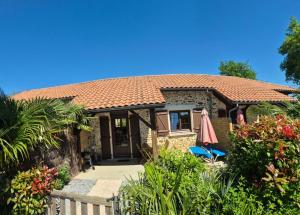 a house with a tiled roof and a patio at renaissance larmane in Eugénie-les-Bains