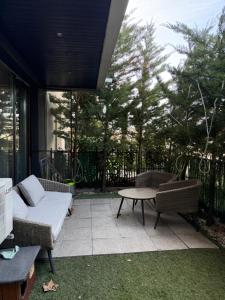 a patio with a couch and a table and some trees at Pipera Garden Apartment in Voluntari
