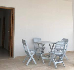 a table and four chairs and a table and a door at Villa blanche sfax in Sfax