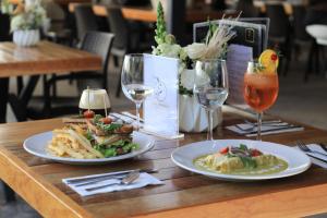 a wooden table with two plates of food and wine glasses at Casa Begonias Hotel mas Villas in Jiutepec