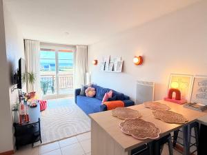 a living room with a table and a blue couch at Au cœur des vignes - Piscine Sauna & Climatisation in Levernois