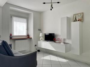 a white living room with a tv and a chair at Cà Marasciol in Villa di Tirano