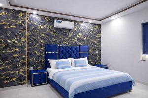 a bedroom with a blue bed and a black and gold wall at Private 2BD Apartment Opposite Dha Phase 8 in Lahore