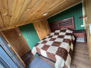 ein Bett in einem Zimmer mit Holzdecke in der Unterkunft tiny house DyL in Puerto Montt
