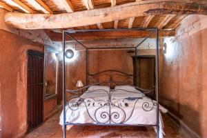 a metal bed in a room with a wooden ceiling at KASBAH DES MONTAGNS maisons d'hôtes la vallée des roses in Bou Drarar