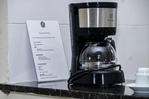 a coffee maker sitting on a counter next to a paper at Hotel Fazenda Arena Green in Cajazeiras