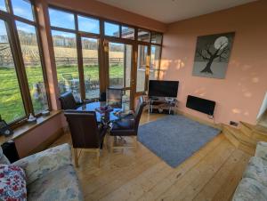 a living room with a table and chairs and windows at Wester Muirhouse in Linlithgow