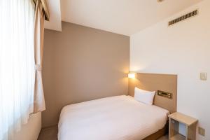 a bedroom with a white bed and a window at 大和パークホテル in Taiwa +1 photo