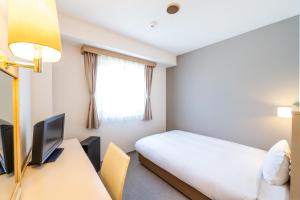 a bedroom with a bed and a desk and a television at 大和パークホテル in Taiwa