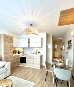 a kitchen and living room with a table and chairs at Sweet Home - Cocon élégant climatisé, piscine été, balcon & parking privé in Chambéry