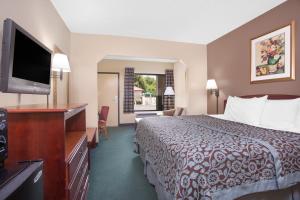 a hotel room with a bed and a flat screen tv at Days Inn by Wyndham Dublin GA in Dublin