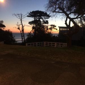 una puesta de sol sobre el océano con una valla y un árbol en Costa Villa, en Atlántida