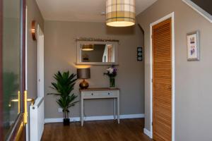 a hallway with a table with a lamp and a mirror at Inskeyft - Kirkwall in Kirkwall +1 photo